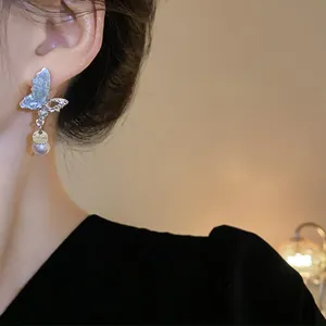 Elegant silver butterfly tassel earring with crystal and pearl details on a model's ear