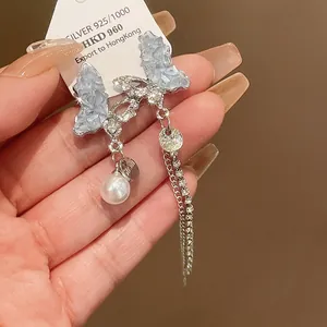 Detailed view of silver butterfly earrings with sparkling crystals and a pearl tassel