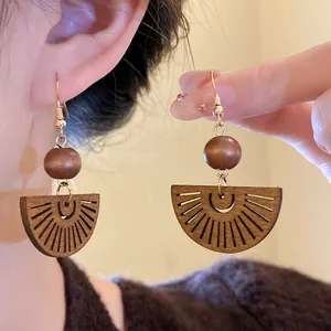 Detailed macro view of bohemian retro hollow wood fan earrings with round beads