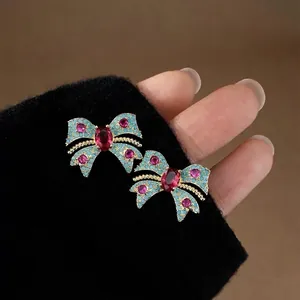 Vista detallada de pendientes de lazo vintage con incrustaciones de circonitas rojas y azules
