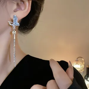 Detailed close-up of an elegant blue crystal butterfly earring with a long sparkling tassel