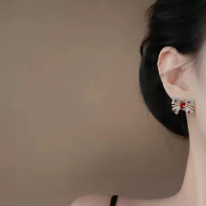 Elegante pendiente de lazo vintage con circón rojo en el perfil de la oreja de la modelo