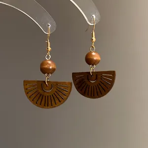 Close-up detail of Bohemian hollow fan-shaped wooden dangle earrings with gold hooks