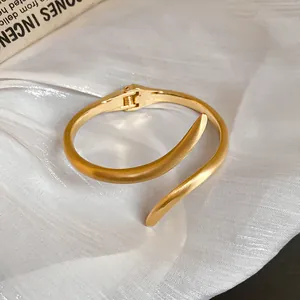 Primer plano de un elegante brazalete de metal dorado con un diseño de cierre de bisagra