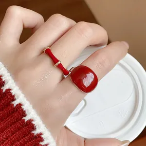 Primo piano di eleganti anelli in smalto rosso placcati in oro 18k con accenti di zircone sulla mano