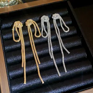 Detailed view of gold and silver retro knot tassel earrings on a black display.