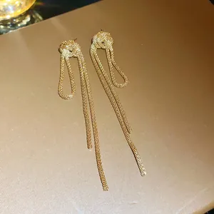 Close-up detail of golden mesh chain knotted tassel earrings with luxurious texture.