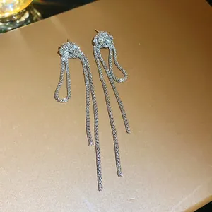 Close-up of silver-toned vintage chain knot tassel earrings on a textured background