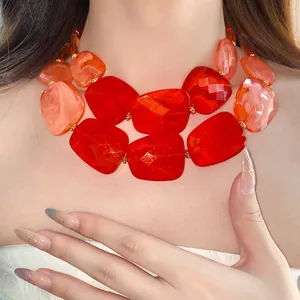 Close-up of a double-layered irregular red acrylic beaded necklace on a model's neck.