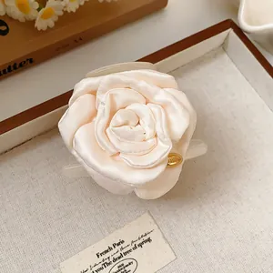 Detailed close-up view of an elegant cream fabric rose hair claw clip with satin texture