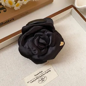 Detailed macro shot of an elegant black fabric rose hair claw clip on a decorative tray.