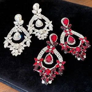 Close-up detail of baroque-style teardrop earrings with clear and red luxury crystals.