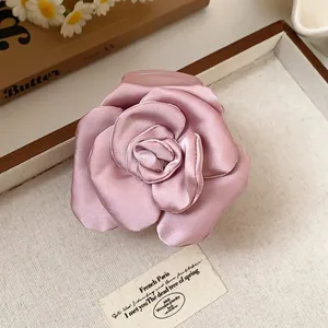 Macro view of elegant pink fabric rose hair claw clip showing smooth satin petal texture