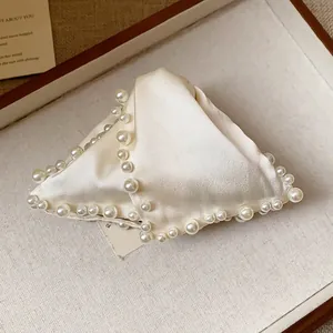 Detailed macro view of an elegant cream satin hair claw clip with decorative pearl edges
