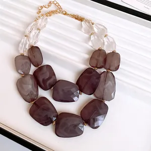 Detail of double-layered chunky necklace with marbled acrylic beads and gold chain.