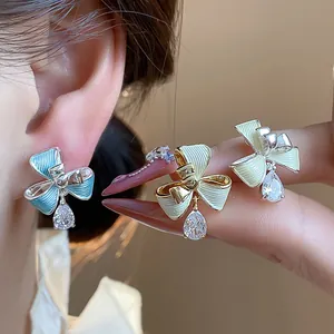 Dettaglio di orecchini a clip a fiocco con zirconi a goccia in tre colori eleganti