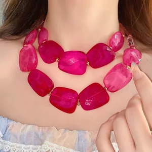 Detailed macro shot of a double-layered necklace featuring faceted magenta acrylic beads