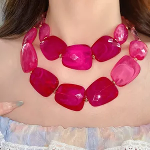 Close-up of a fuchsia double-layered acrylic beaded necklace with marbled texture