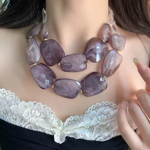 Macro view of purple marbled and faceted acrylic beads on a double-layered necklace