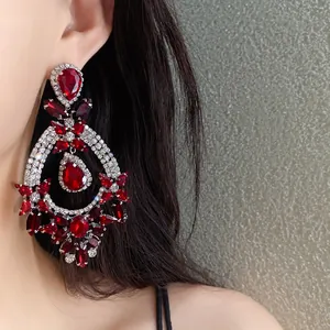 Close-up of palace style red drop earrings with silver flower and rhinestone details.