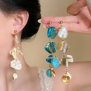 Close-up of irregular shell dangling earrings with bohemian summer vacation vibes