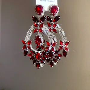 Detail view of ornate red crystal drop earrings with sparkling rhinestone accents.