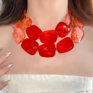 Close-up detail of irregular red and orange acrylic beads on a double-layer statement necklace