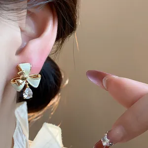 Dettaglio ravvicinato di un orecchino a fiocco placcato oro 18k con goccia di zircone brillante.