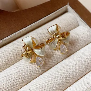 Dettaglio ravvicinato di eleganti orecchini a clip a fiocco placcati in oro 18k con zirconi