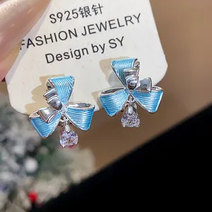 Dettaglio di orecchini a clip a fiocco in smalto blu con pendente in zircone brillante
