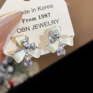Dettaglio degli orecchini a clip a fiocco placcati oro con pendente in zircone