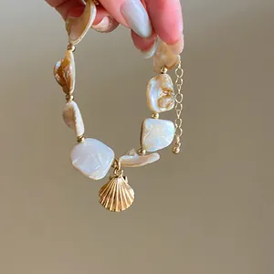 Elegant seashell and pearl necklace with irregular gold beads and shell charm.