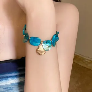 Summer resort style blue shell fragment bracelet featuring a gold seashell charm detail