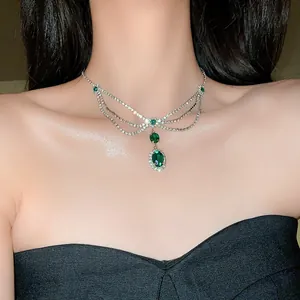 Close-up view of vintage green oval gemstone necklace with rhinestones worn by a model