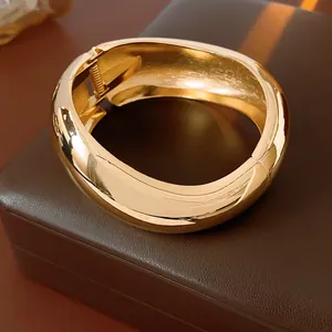 Bracciale rigido dorato lucido con chiusura a cerniera dal design bombato