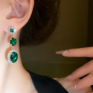 Close-up of elegant emerald green dangling earrings with sparkling rhinestone accents