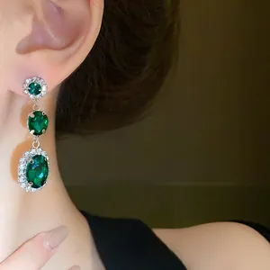 Detail of vintage palace style green emerald drop earrings with halo crystals