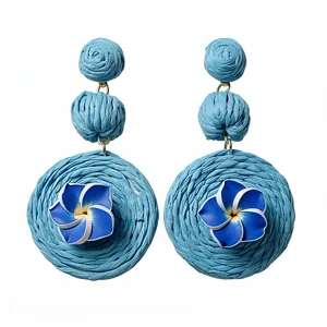 Handmade blue raffia woven drop earrings with plumeria flower design for a resort style look