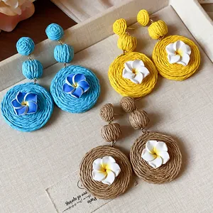 Detailed view of handmade raffia earrings with white clay flowers in multiple colors