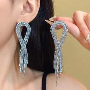 Detailed macro view of sparkling luxury zircon geometric tassel earrings on a model.