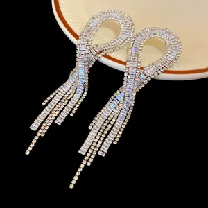 Macro view showing the sparkle of long zircon geometric tassel earrings on a plate
