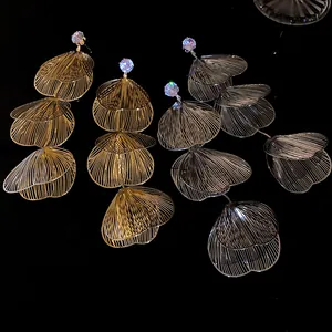 Detailed view of tiered metal petal earrings with sparkling rhinestone studs on black background.