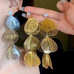 Detailed view of exaggerated gold and silver floral wire-frame tassel earrings.