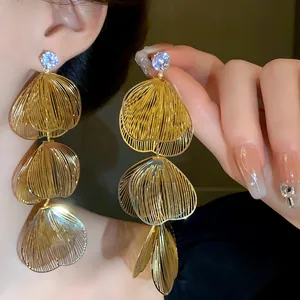 Close-up detail of layered gold petal earrings with sparkling rhinestone studs.