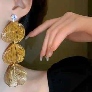 Detail view of gold tiered petal tassel earrings with elegant rhinestone studs
