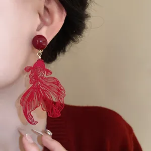 Close-up detail of red goldfish hollow-out clip-on earrings in elegant New Chinese style