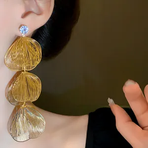 Close-up of gold layered petal tassel earrings with sparkling rhinestone stud detail