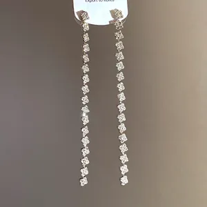 Detail of long square rhinestone tassel earrings with sparkling crystals for elegant look.