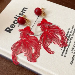Intricate detail of red hollowed-out goldfish clip-on earrings with gold ball studs