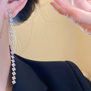 Close-up detail of elegant square rhinestone tassel earrings on a model